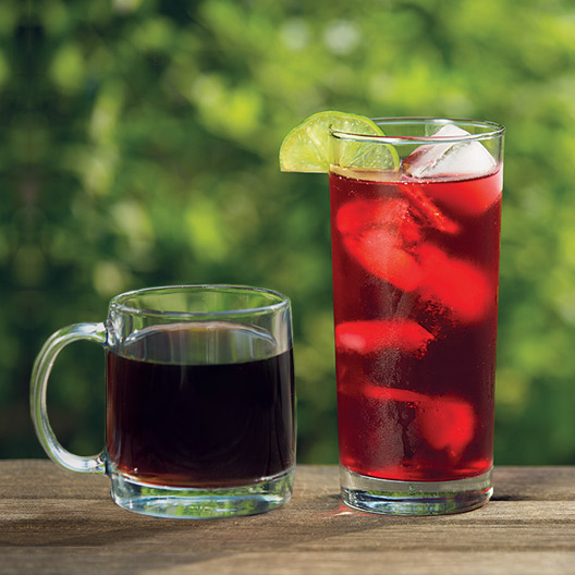 side by side photo of a glass of cold brew coffee and hibiscus tea over ice with a lime wedge on the rim sitting on a table outside